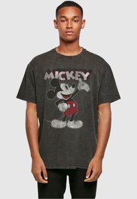 T-shirt noir à manches courtes avec un motif Mickey Mouse vintage en rouge et blanc. Tissu doux et texturé avec une coupe décontractée.