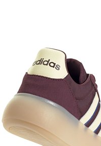 Bordo suédne tenisice s kremastim kožnim ovratnikom, koje imaju tri bijele i plave pruge te prozirnu gumenu potplat.