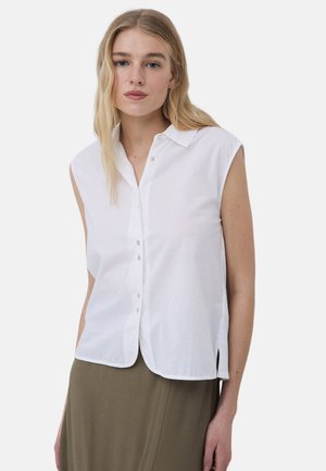 Camisa sin mangas de cuello blanco con cierre de botones en la parte frontal, que cuenta con botones de acento azules y aberturas laterales, hecha de una tela ligera.