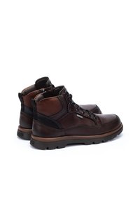 Brown leather ankle boots with black accents, rounded toe, sturdy lace-up design, textured surface, and rubber soles for grip.