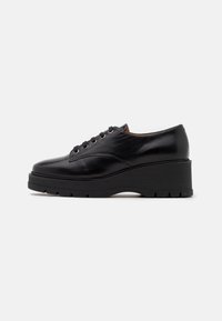 Scarpe in pelle nera con punta arrotondata, sei fori per i lacci e una suola in platform nera spessa e tessurizzata per un'altezza aggiuntiva.