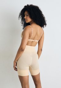Pánt nélküli formáló bodysuit, varrás nélküli kialakítással, magas derékkal és combközép hosszúsággal. Állítható pántokkal és sima, rugalmas anyaggal rendelkezik.