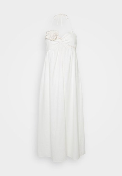 Vestido halter blanco hecho de una tela liviana, con un detalle de flor en un lado y un diseño de falda fluida. Textura larga y suave.