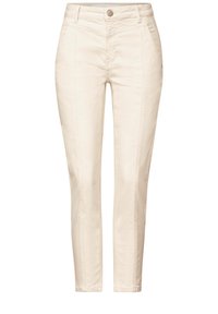 Pantalones de algodón beige con corte ajustado, que cuentan con bolsillos frontales, cierre de botón y detalles de costura vertical a lo largo de los lados.