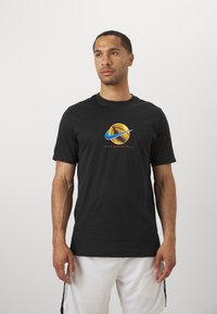 Camiseta de manga corta negra de algodón, con un gráfico de baloncesto multicolor y el texto "Nike Basketball" en el frente.