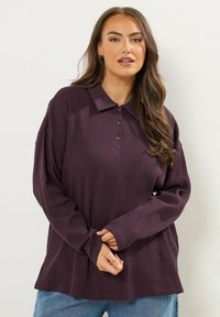 Langsleeve polo shirt in pruimkleur met een gestructureerde stof, drie knoopsluitingen en zijsplitten voor een relaxte pasvorm.