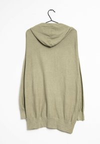 Olive green oversized hoodie with long sleeves, made of soft, textured fabric, featuring a rounded hood and a straight hem. Hangs from a hook.