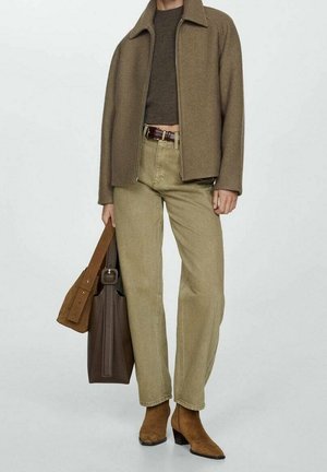 Bruine wolmix jas, olijfgroene spijkerbroek, bruin riem, bruine leren tas en bruine enkellaarzen. Eenvoudig ontwerp met textuurstoffen.