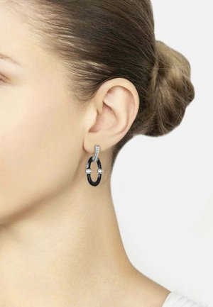 Black and silver earrings featuring a curved, linked design with small gemstones at the ends, suspended from a silver decorative post.