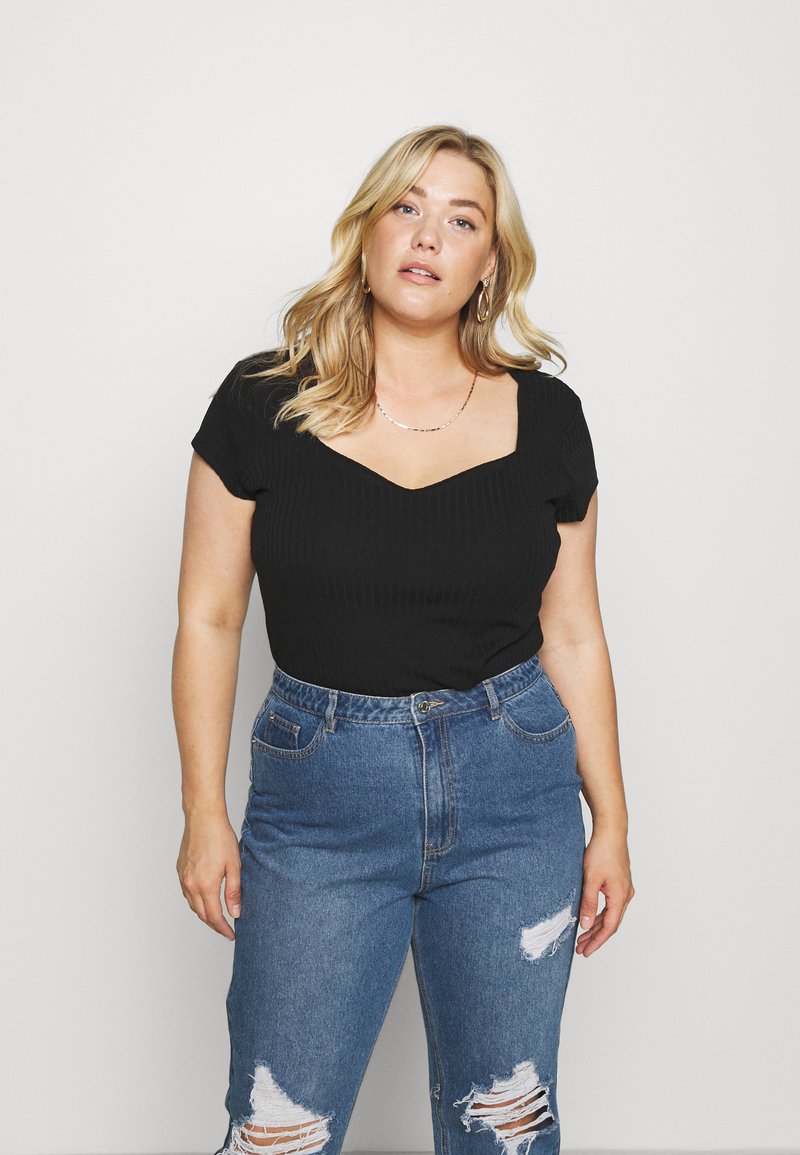 Zwart geribbelde top met korte mouwen en een vierkante halslijn, gecombineerd met lichtblauwe jeans met hoge taille en vernevelde knietjes.