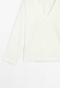 Witte lange mouw top met een diepe V-hals. Gemaakt van soepel materiaal, met een losse pasvorm en zijsplitten bij de zoom.