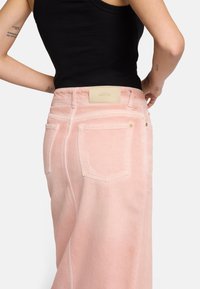 Jupe en denim rose à taille haute, dotée d'une étiquette en cuir, de deux poches arrière et de légers effets de décoloration. Texture lisse.