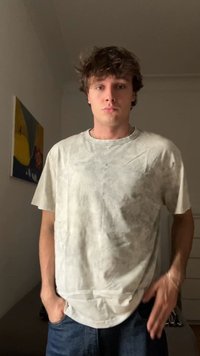 Lys grå tie-dye t-skjorte med korte ermer, rund hals og løs passform. Stoffet fremstår som mykt med en lett teksturert overflate.