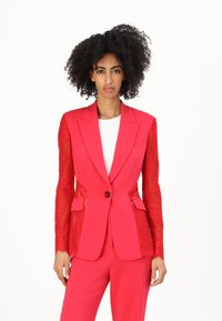 Rode, op maat gemaakte blazer met doorschijnende kantmouwen, enkele knoopsluiting, notch revers en zijzakken, gecombineerd met bijpassende op maat gemaakte broek.