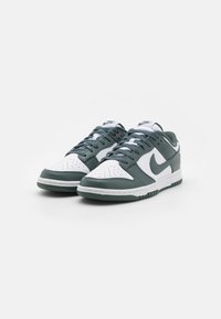 Nike Dunk sneakers with a white and dark green leather upper, featuring perforated toe, white laces, and green rubber sole.