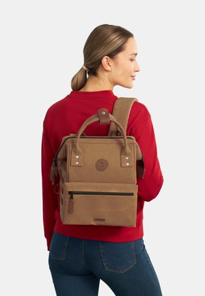 Brauner Canvas-Rucksack mit Obergriff, Reißverschlussfächern und verstellbarem Gurt. Enthält ein Logo-Patch und verstärkte Nähte.