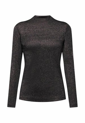 Haut noir à manches longues avec un effet scintillant, doté d'un col montant et assorti à une jupe argentée métallique et une ceinture blanche.