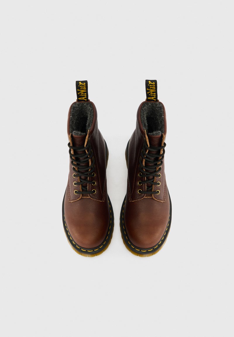 Braune Leder-Stiefeletten mit runden Zehen, schwarzen Schnürsenkeln und einem gelben Nahtakzent. Sie haben einen gepolsterten Kragen und eine Zuglasche an der Rückseite.