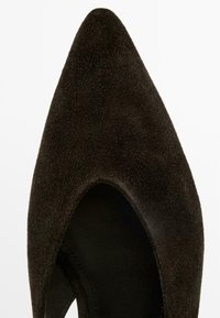 Scarpa da donna in suede marrone scuro con punta appuntita, apertura bassa e texture liscia, vista dall'alto su sfondo bianco.