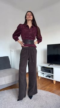 Burgundy suede button-up shirt with puffed sleeves, paired with brown corduroy wide-leg pants and black pointed heels. Simple black belt accent.