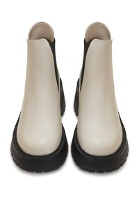 Botas de tobillo de cuero beige con paneles laterales elásticos negros y suelas gruesas de goma negra con relieve. Diseño sencillo con una textura suave y mínimas ornamentaciones.