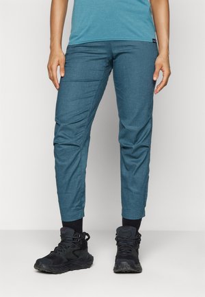 Pantalons bleus fuselés en tissu texturé avec des cuffs élastiques, accompagnés de chaussures de randonnée légères noires dotées de lacets et de semelles rembourrées.