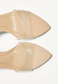 Klare Heeled Mules mit spitzem Zehenbereich. Mit transparenten Riemen und einer nude-farbenen, strukturierten Innensohle. Schlankes Design, minimalistische Beschläge.