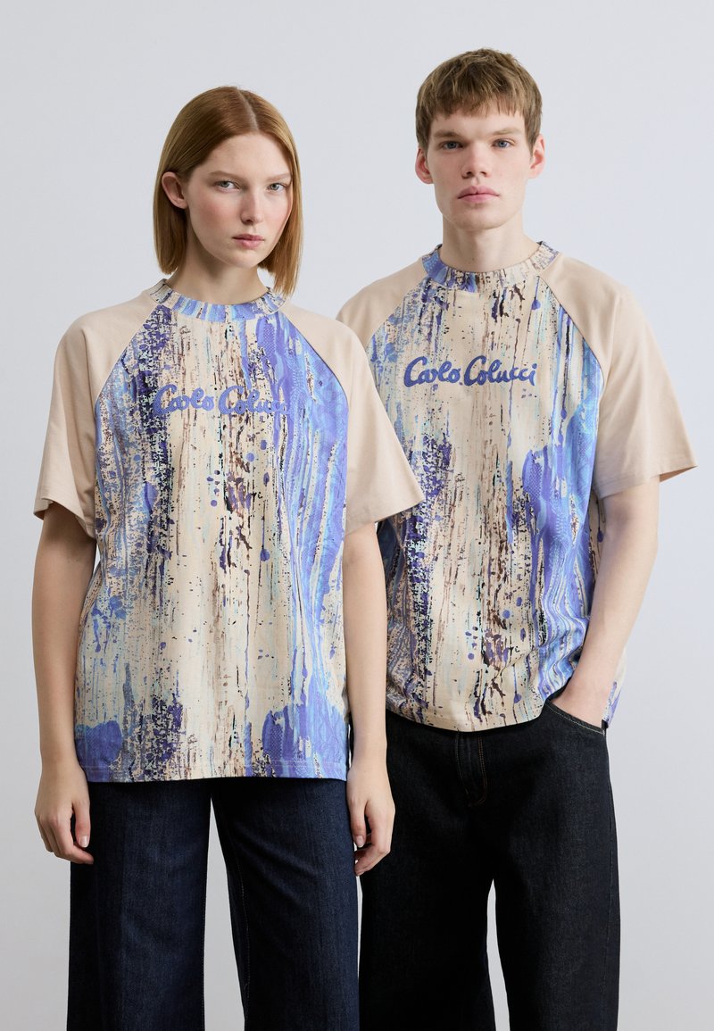 Κοντομάνικα, μπεζ και μπλε t-shirts με αφηρημένο σχέδιο πιτσιλιών χρωμάτων. Κείμενο «Carlo Colucci» στο μπροστινό μέρος, μανίκια ράγκλαν, άνετη εφαρμογή.