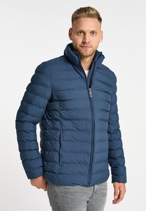Blauer gepolsterter Mantel mit hohem Kragen, Front-Reißverschluss und horizontalen Steppdetails. Verfügt über lange Ärmel und eine taillierte Silhouette.