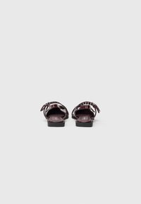 Sandales plates bordeaux avec une finition lisse et brillante, bout ouvert et bride de cheville ajustable. Forme à bout carré et talon bas.