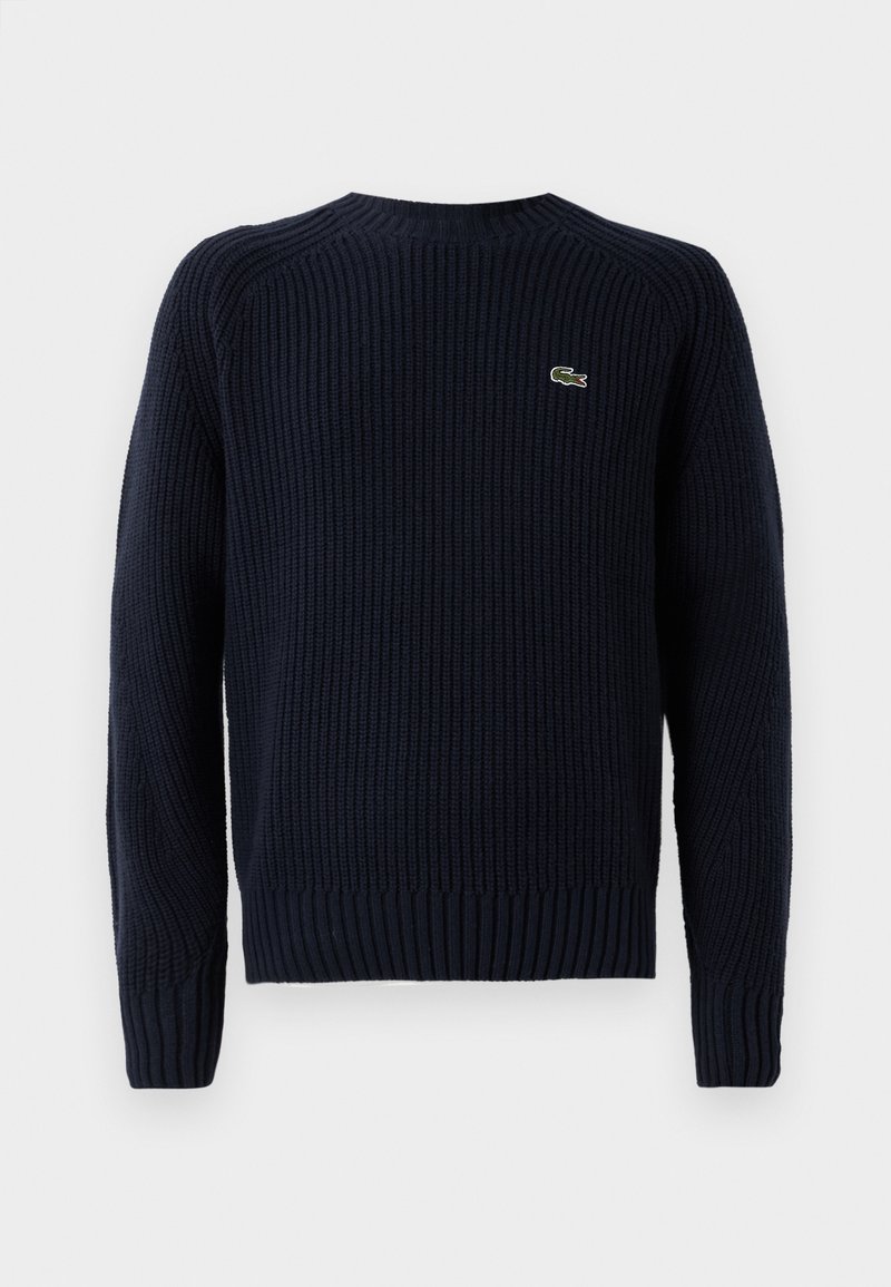 Marinblå stickad tröja med ribbad textur, rund halsringning och långa ärmar. Har en liten grön logotyp på övre vänstra ryggen.