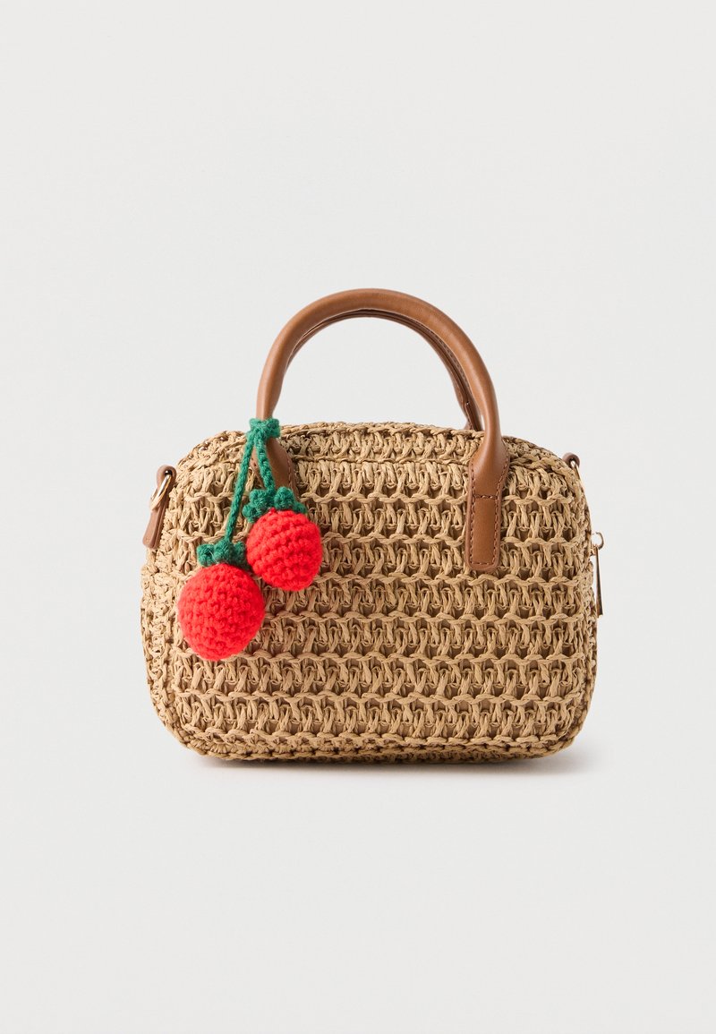 Petit sac à main en paille tressée avec des poignées en cuir marron et deux cerises rouges au crochet attachées par des tiges vertes sur le devant.