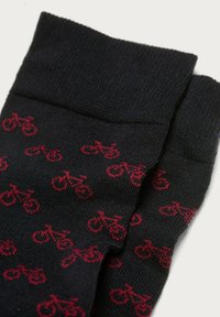 Calzini neri con un motivo ripetuto di piccole biciclette rosse, realizzati in un tessuto di maglia testurizzato con un orlo a coste.
