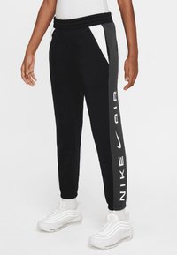 Black jogger pants with white accents, Nike Air branding, elastic waistband, and tapered ankle fit. Made from soft, breathable material.