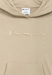 Μπεζ φούτερ με κουκούλα που διαθέτει κεντημένο λογότυπο «Champion», τσέπη καγκουρό και ετικέτα με την ένδειξη μεγέθους S, κατασκευασμένο στην Καμπότζη.