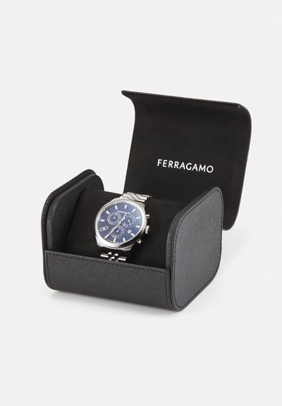 Stainless steel watch with a blue dial, chronograph features, and silver accents, displayed in a black textured leather case.