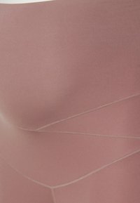 Close-up of smooth pink fabric with visible stitching lines forming geometric patterns.