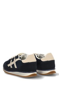 Zapatillas azul marino con acentos beige, material de ante y malla, punta redondeada, suela de goma blanca y tres rayas blancas en el lateral.