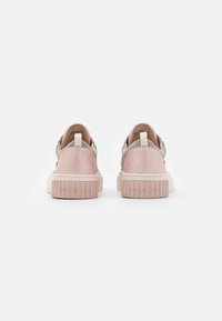 Sneakers in suede rosa con un accento metallico testurizzato, caratterizzati da una suola bianca spessa e un tallone con marchio, progettati per comfort e stile.