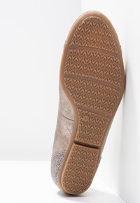 Vue de la semelle de chaussure avec du caoutchouc texturé en motif ondulé, couleur beige clair, et un accent scintillant près de la section du talon. Taille indiquée comme 37.