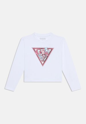 Valkoinen pitkähihainen crop-top, jossa on kolmiomainen graafinen muotoilu ja monivärinen "GUESS"-teksti, jossa on vaaleanpunaista, sinistä ja mustaa korostusta.