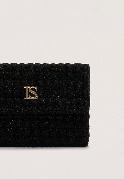 Juodos pintos rankinės su tekstūruotu paviršiumi, su auksiniu logotipo akcentu priekyje, uždaromos užsegimu su sklende. Kompaktiška ir stačiakampė forma.