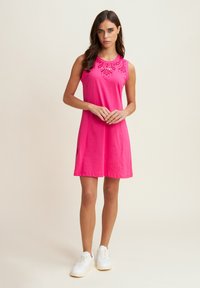 Vestido rosa sin mangas con un escote redondeado, que presenta bordados decorativos en los hombros. Tejido suave con un corte relajado.