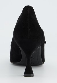 Chaussure à talon haut en daim noir avec un bout pointu et un talon fin. L'arrière présente une texture lisse avec des détails de coutures subtils.