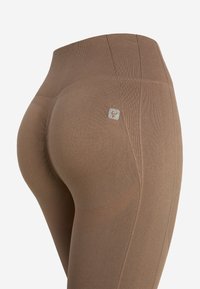 Leggings marroni a vita alta, con texture a coste, tessuto morbido e una piccola etichetta logo sul lato. Il design aderente mette in risalto la forma.