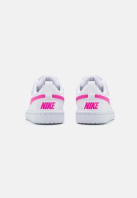 Hvide sneakers med lyserøde accenter, der har en glat læderoverdel, polstret krave og fremtrædende Nike-branding på hælen og siden.