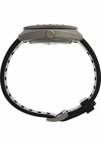 Vue de côté d'une montre-bracelet avec un boîtier gris, une lunette striée et un bracelet réglable noir et blanc avec une boucle en métal.
