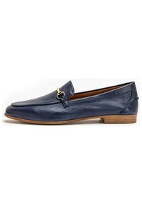 Mocasin de cuero azul marino con tacón de madera plano, que presenta un acento de hebilla en tono dorado y una textura suave, destacando su diseño clásico.