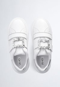 Hvide sneakers med en glat læderoverflade, en dekorativ rem med klare ædelsten og et rundt logo på spænde.