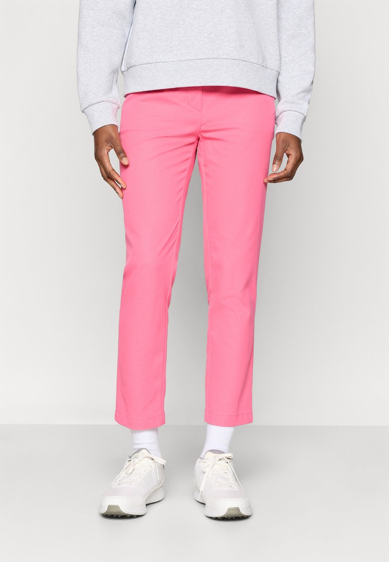 Rozā kokvilnas bikses ar šauru piegriezumu un saīsinātu garumu, kombinētas ar baltām sporta kurpēm un pelēku svīteri. Gluda tekstūra un nav redzamu rakstu.